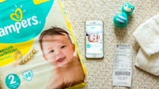 Pampers, eine App und ein Kassenbon auf einem Fußboden.