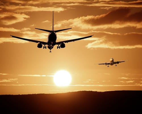 Booking.com-Flüge Zwei Flugzeuge beim Sonnenuntergang
