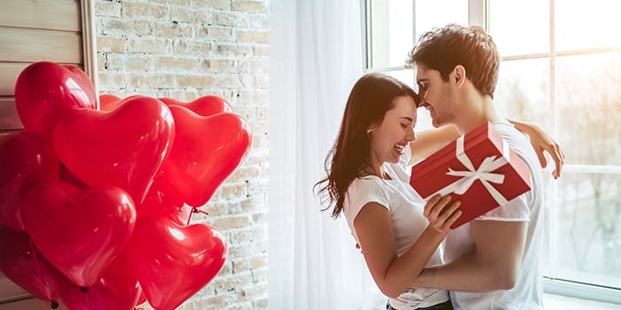 Zum Tag der Liebe: Gutscheine für den Valentinstag Mann übergibt seiner Freundin ein Valentinstagsgeschenk