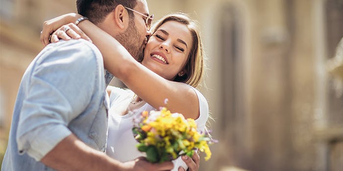 Valentinstag: Gutscheine und Geschenkideen Ein Mann küsst eine Frau, sie lächelt.