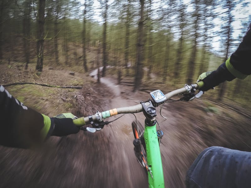 Blick über den Fahrradlenker bei Downhill-Fahrt im Wald