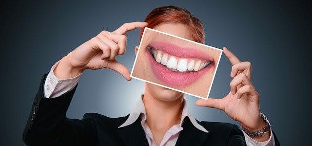 Frau hält Bild eines Lächelns in den Händen