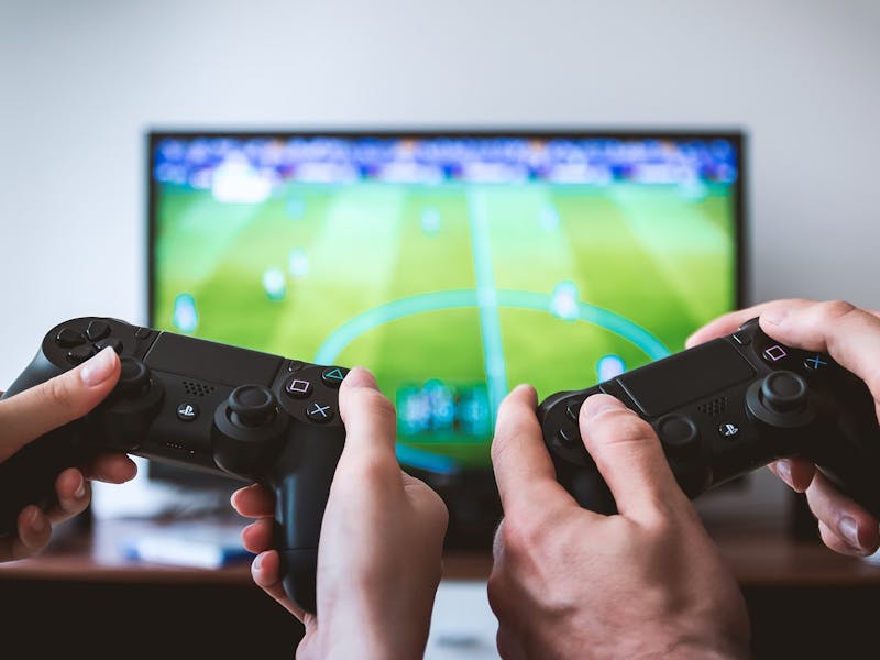 Zwei Konsolen-Controller, im Hintergrund ein Fernseher