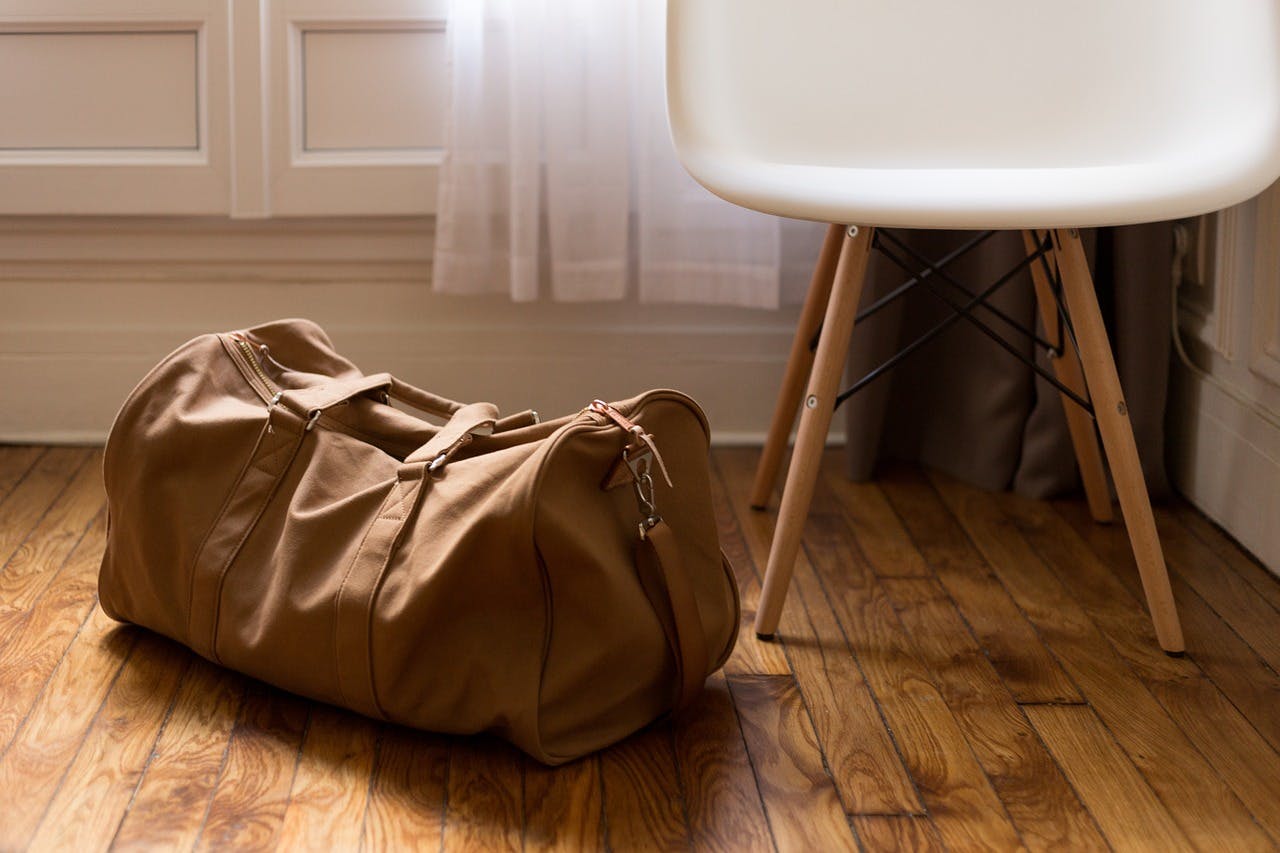 Stilwahl_Reisetasche Braune Reisetasche neben einem weißen Stuhl