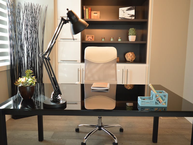 Ein Arbeitszimmer mit Tisch und Bürostuhl sowie einer Lampe.