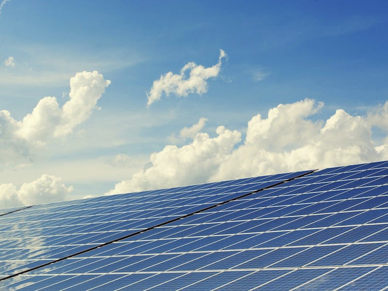 Eine Solaranlage, im Hintergrund ein paar Wolken am Himmel.