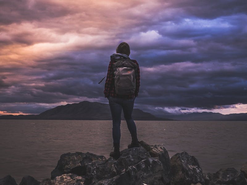 Eine Frau steht auf einem Felsen und schaut über das Meer.