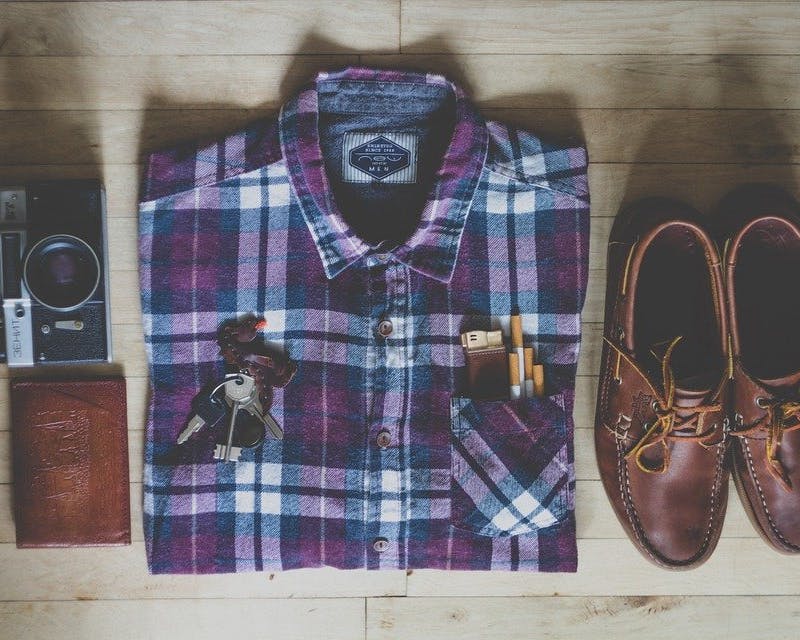 Breuninger Herrenmode Gefaltetes Hemd, Schuhe und Accessoires auf Tischplatte