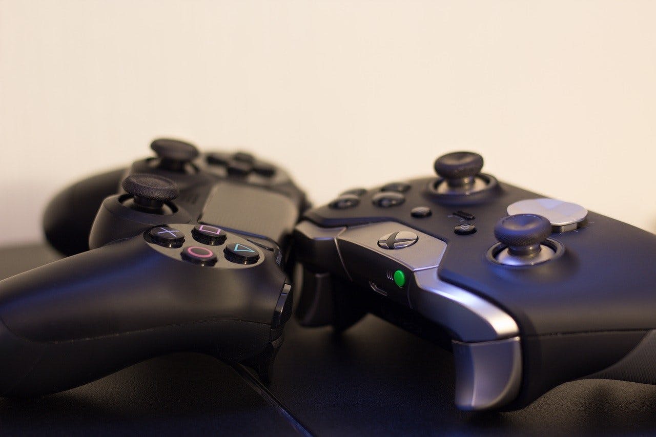Videospiele Gutschein Xbox und Playstation Controller liegen nebeneinander