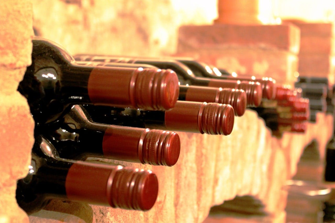 Flaschenpost_Weinkeller Rotwein-Flaschen nebeneinander aufgereiht im Weinkeller