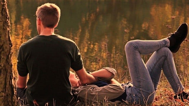 Paar sitzt und liegt auf abendlicher Sommerwiese