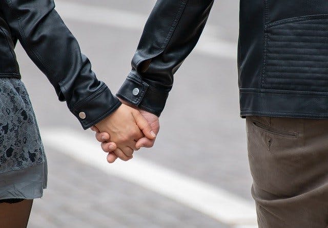 Frau und Mann halten Händchen. Lederjacke