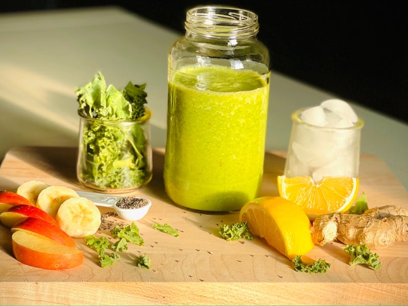 Aufgeschnittene Früchte und Smoothie auf Holzbrett