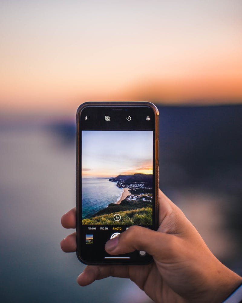 Sonnenuntergang an der Küste wird mit Smartphone fotografiert