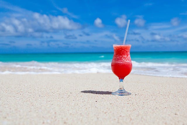 Ein Cocktail am Strand Ein roter Cocktail mit Strohhalm an einem Strand