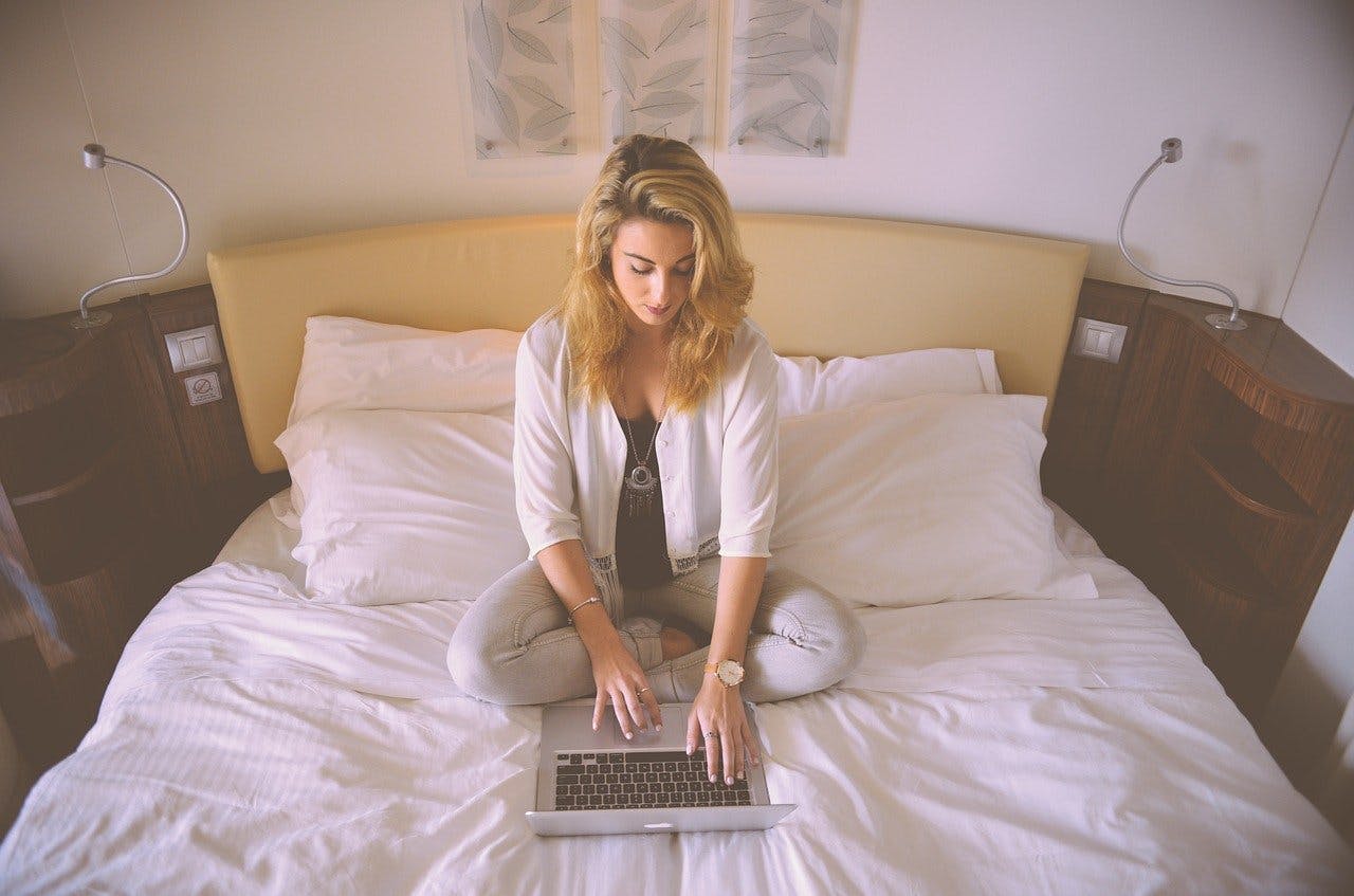 Frau arbeitet mit Laptop im Bett