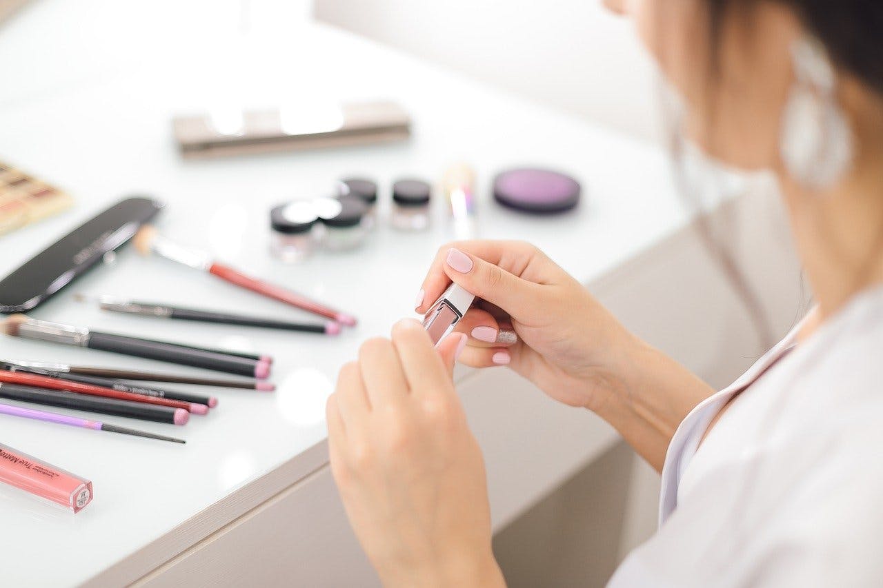 asambeauty Gutschein Frau hält an ihrem Schminktisch Lippenstift in Händen