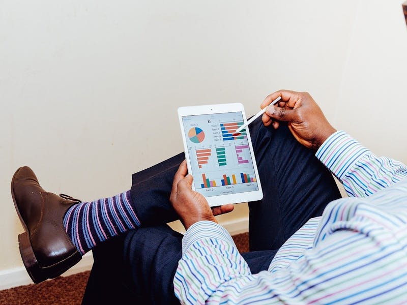 Ein Mann hält ein Tablet in der Hand und hat gestreifte Socken an