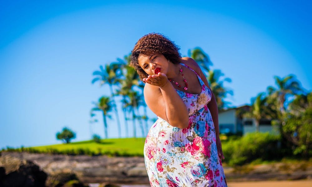 Plus Size Model im Blumenkleid vor Palmen und blauem Himmel