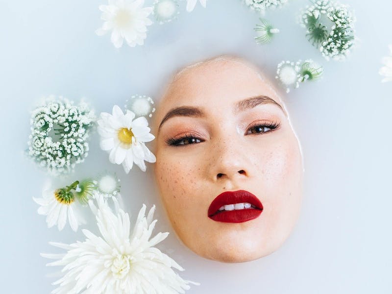 Hübsche Frau im Wasser mit Blumen