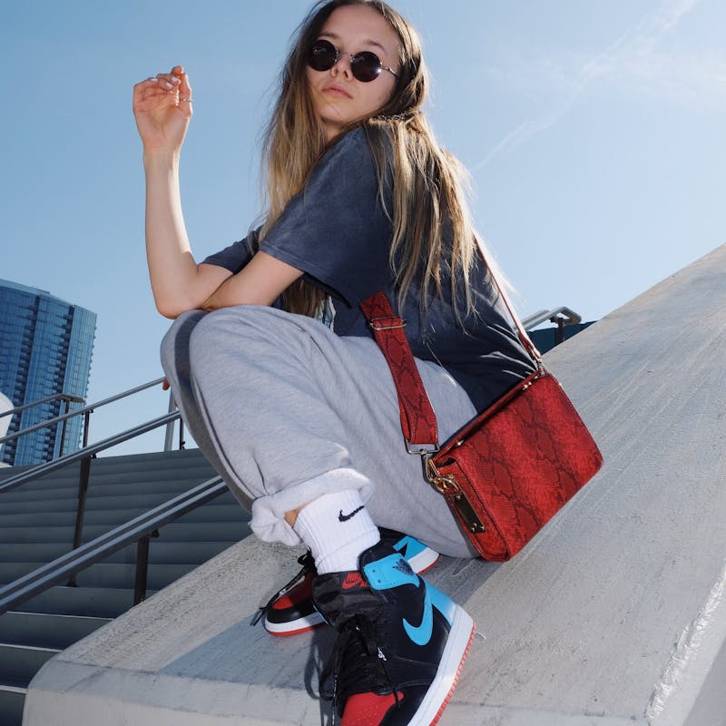Junge Frau mit Streetwear und Sneakern auf Betontreppe