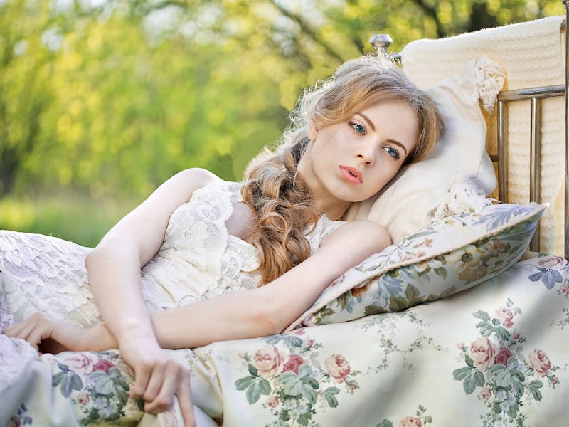 Eine Frau liegt in der freien Natur auf einem Bett