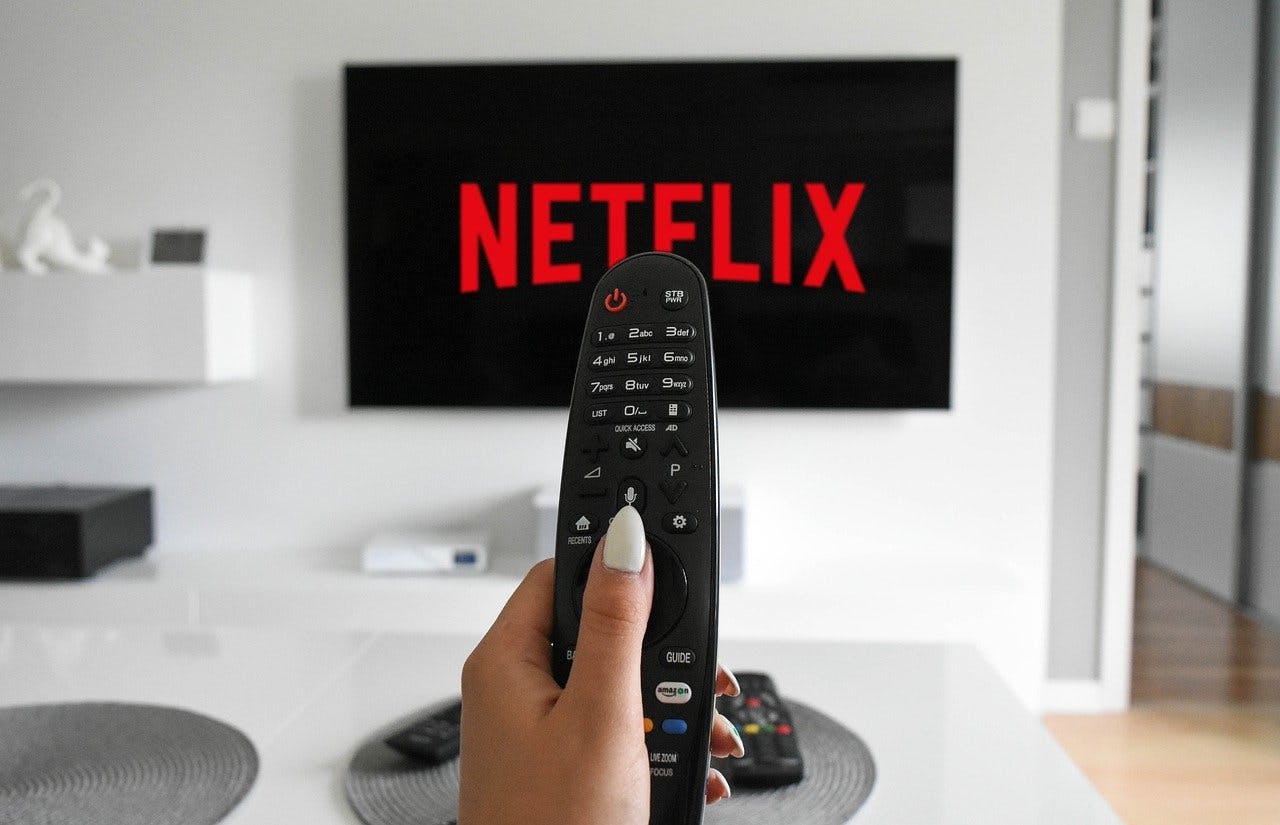 Netflix Gutschein Frau mit Fernbedienung in der Hand schaltet auf Ihrem Smart-TV Netflix ein