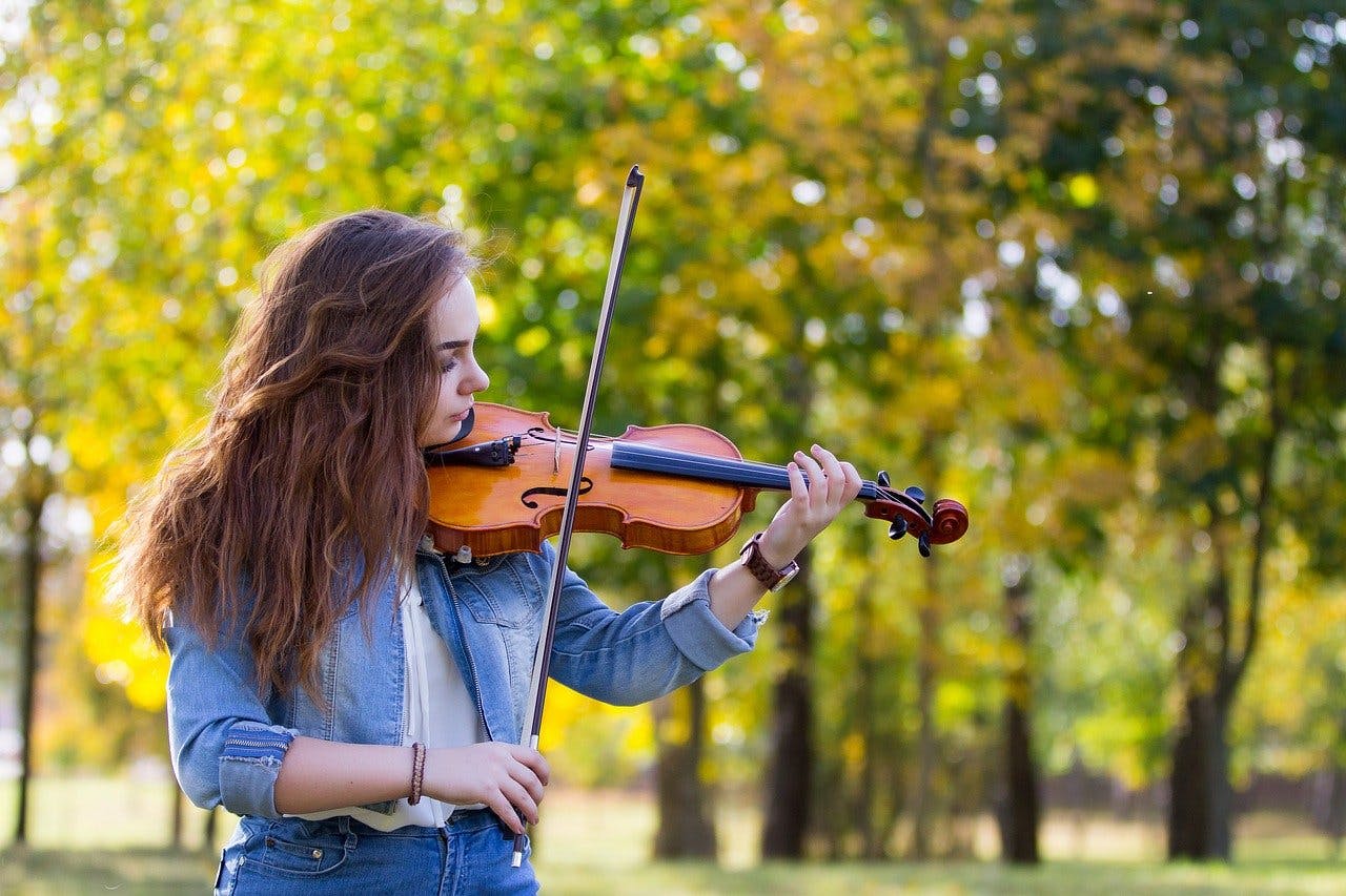Hobby Gutschein Junge Frau spielt im Freien Geige