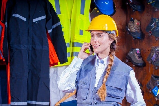Frau in Arbeitskleidung und Bauhelm