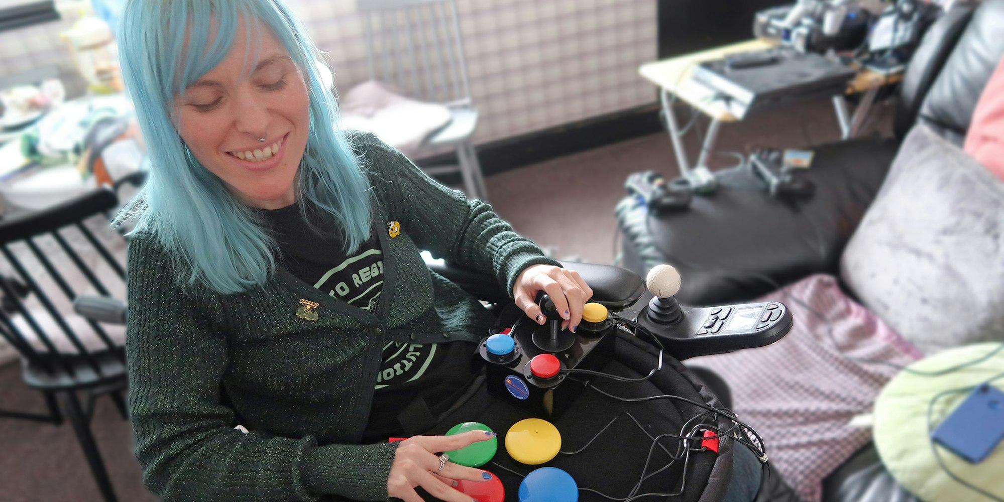 a lady with blue hair plays with a selection of brightly coloured buttons on a pad on her lap