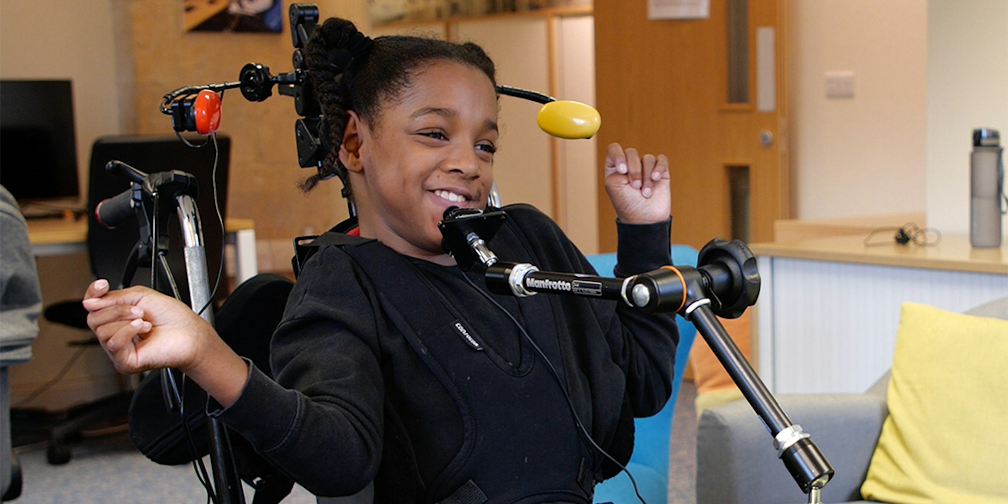 a young girl plays with a small joystick mounted at chin level