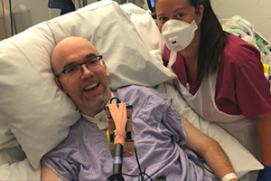 smiling man in hospital bed, nurse alongside
