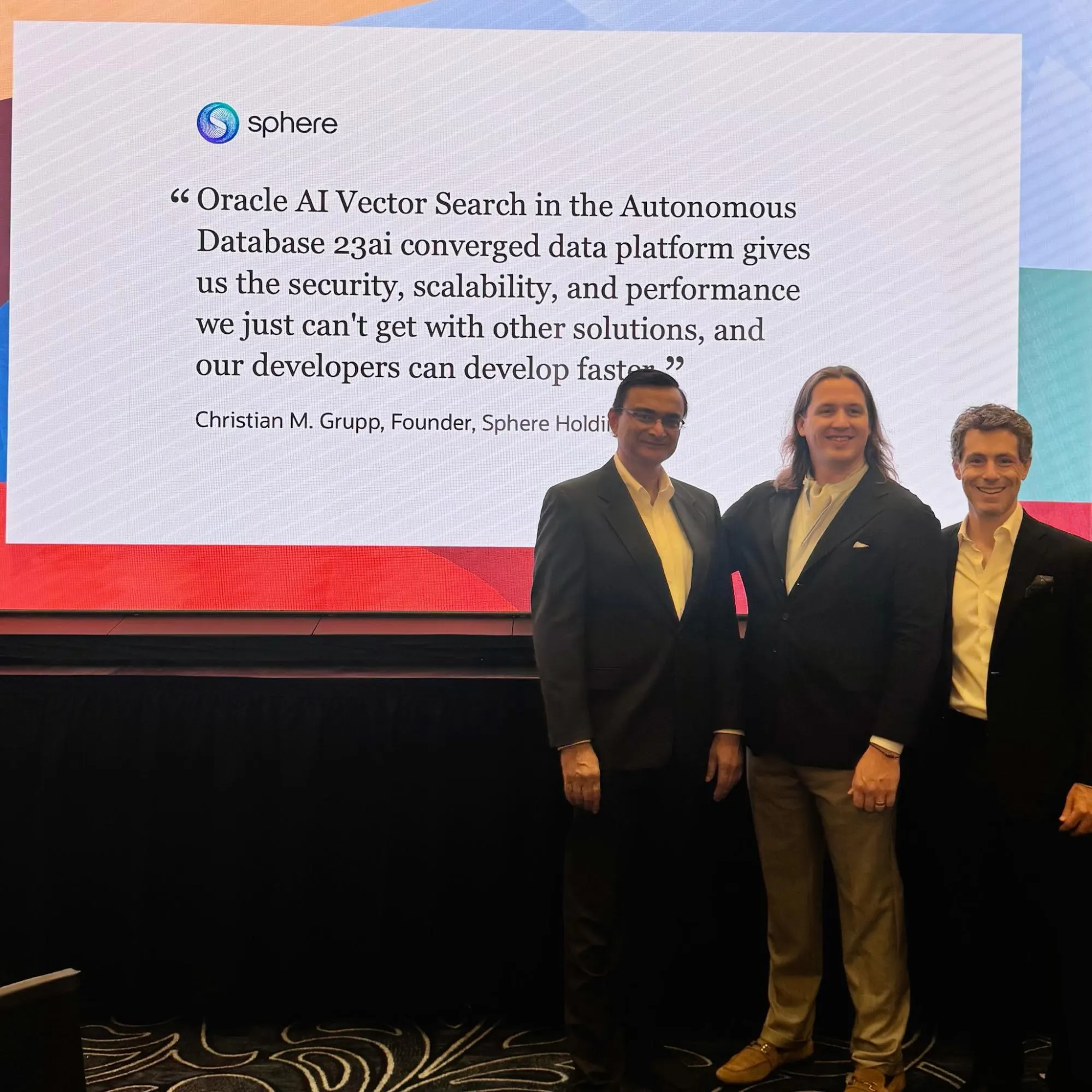 Christian Grupp with two colleagues in front of a Sphere slide at Oracle AI World 2025 quoting him on Oracle AI Vector Search in Autonomous Database 23ai.
