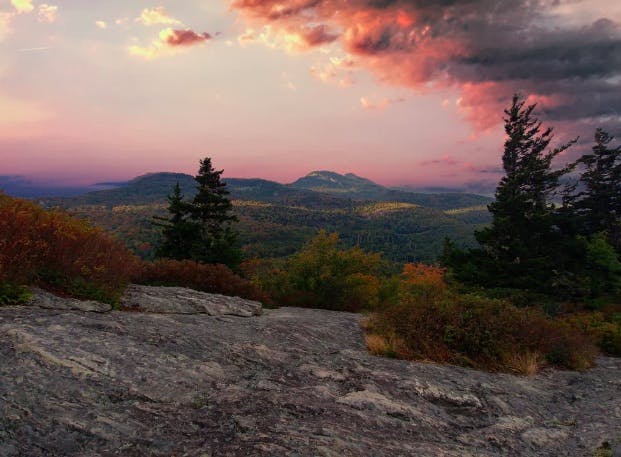 Mountain landscape with cliffs, bushes, trees and clouds