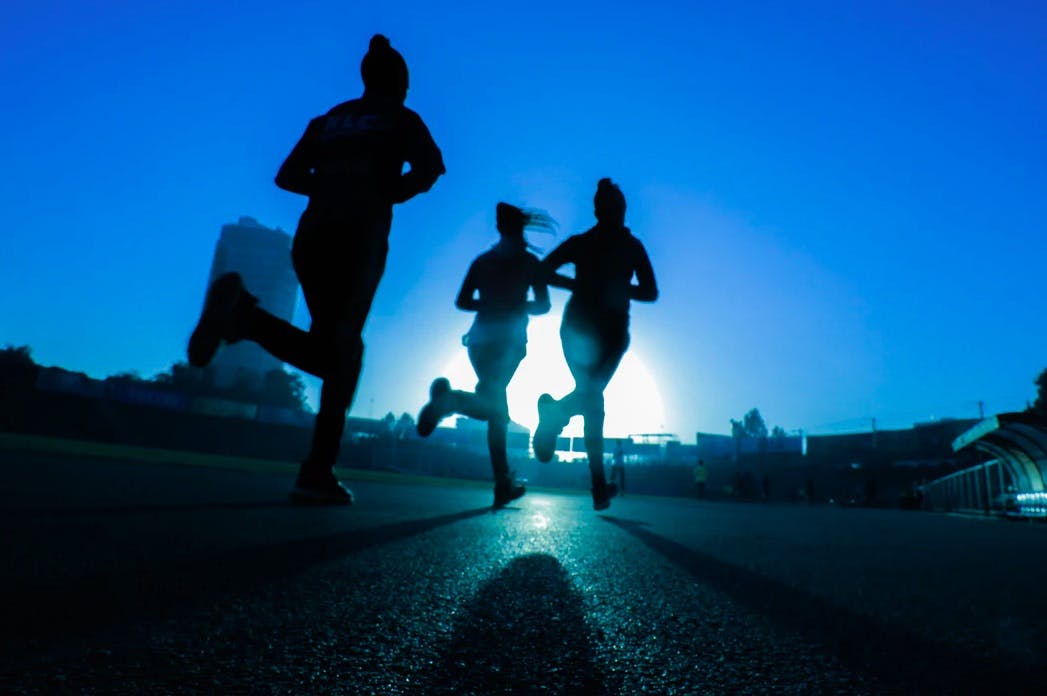 Three women running on the road in the evening