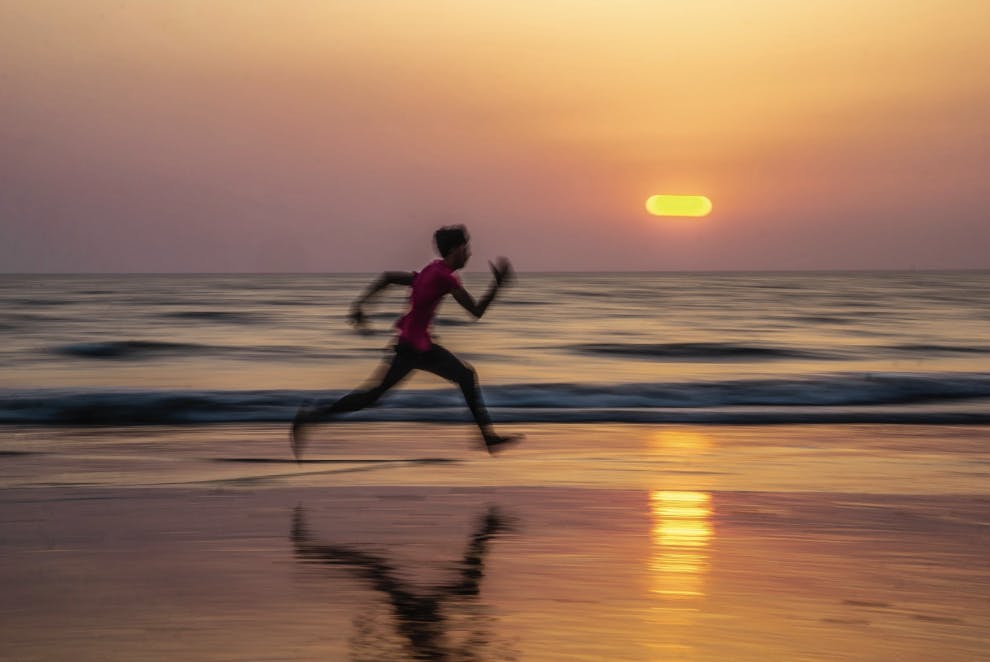 boy sprinting on beach sunset