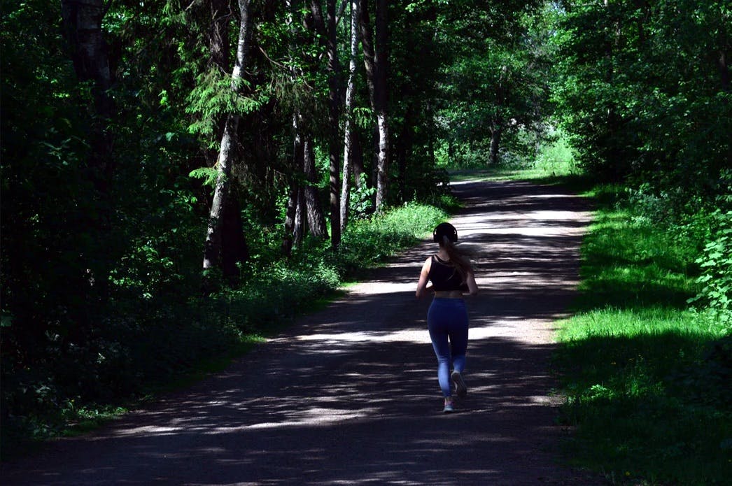 Woman with earphones, running in the forest