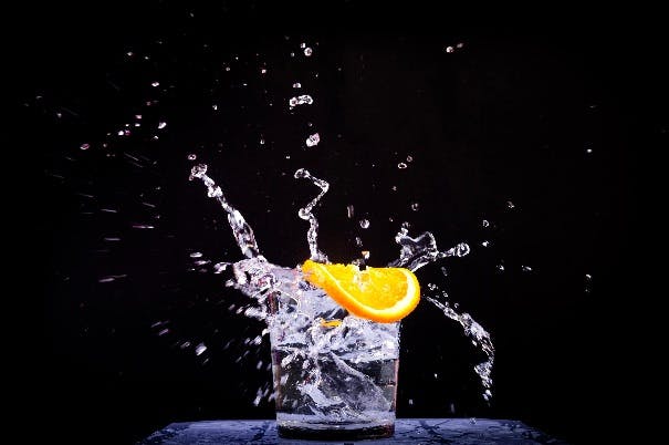 A glass of sparkling water and a slice of lemon on a black background