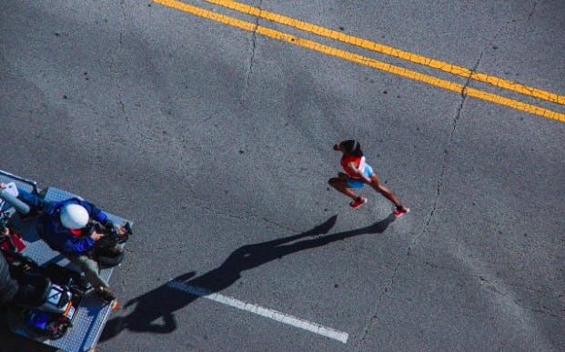 View from above of a woman running on asphalt