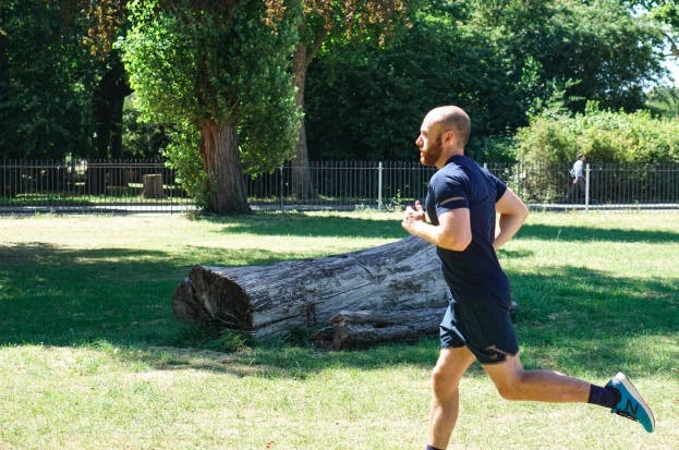 Man running along a fence, passing by a log