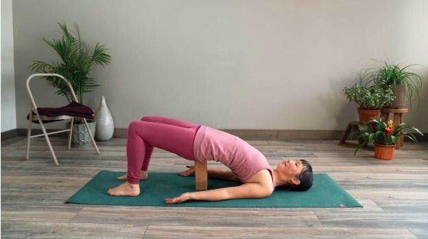 Woman doing the supported bridge pose to strengthen her knees
