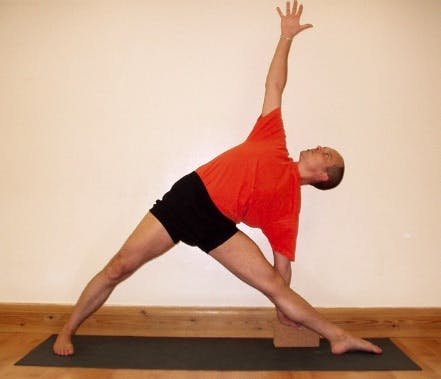 Man doing a yoga move called the Triangle Pose in order to help his knees