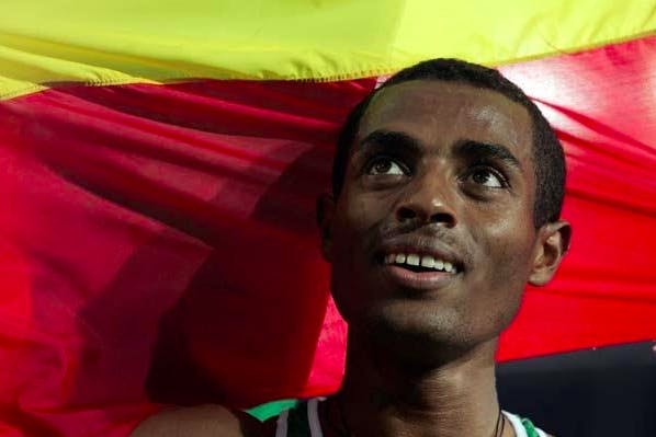 Close-up of Kenenisa Bekele in front of the Ethiopian flag