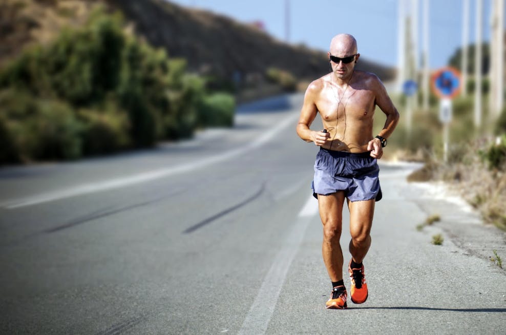 shirtless man running on road