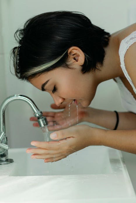 Close-up of a young woman washing her face in the bathroom