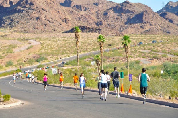 View from behind of people running a marathon on a winding road through the mountains