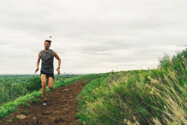 Man dressed in grey top and short pants running on a field