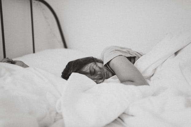 Woman sleeping o a bed with white sheets