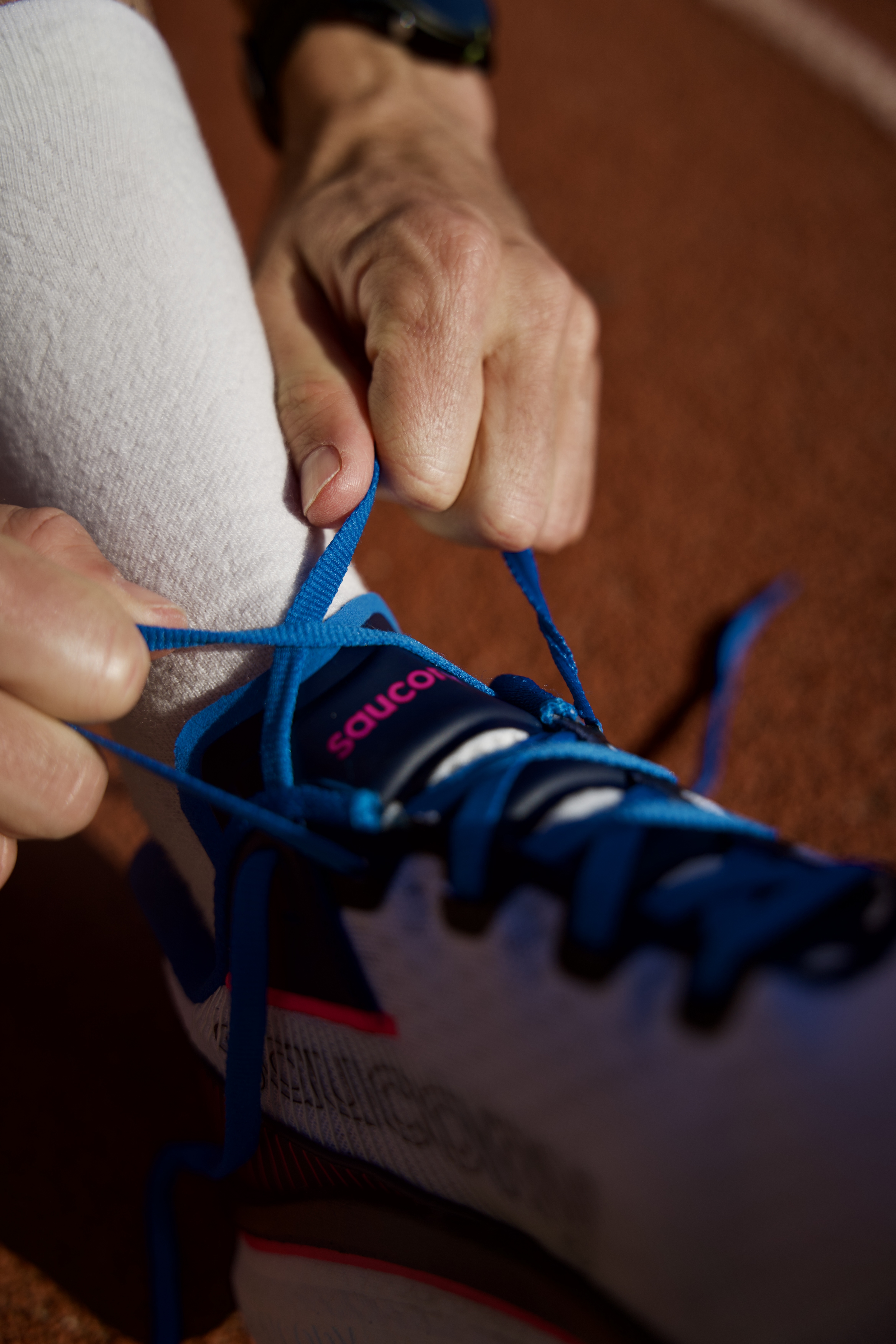 close-up-of-hands-lacing-up-saucony-azura-endorphin-trainers