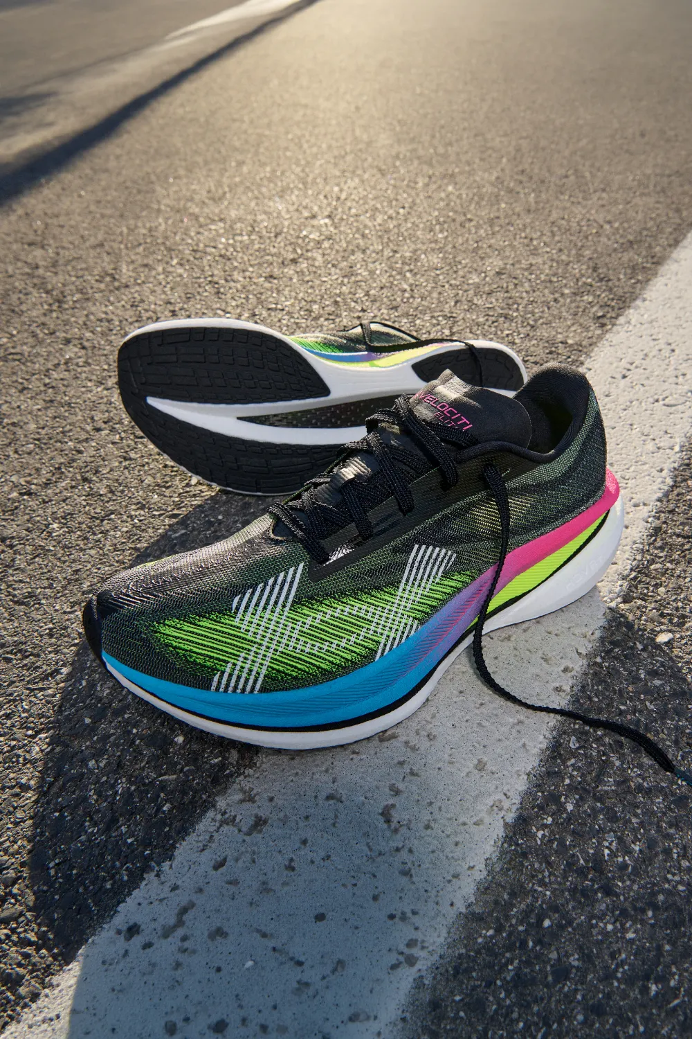 Carbon plate racing shoes shown on a road with green and pink neon accents for high-performance marathon running.